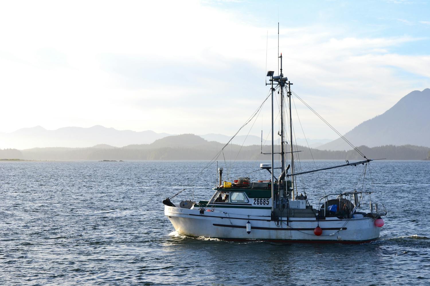 A charter boat on glass-calm Alaskan water beneath the mountains